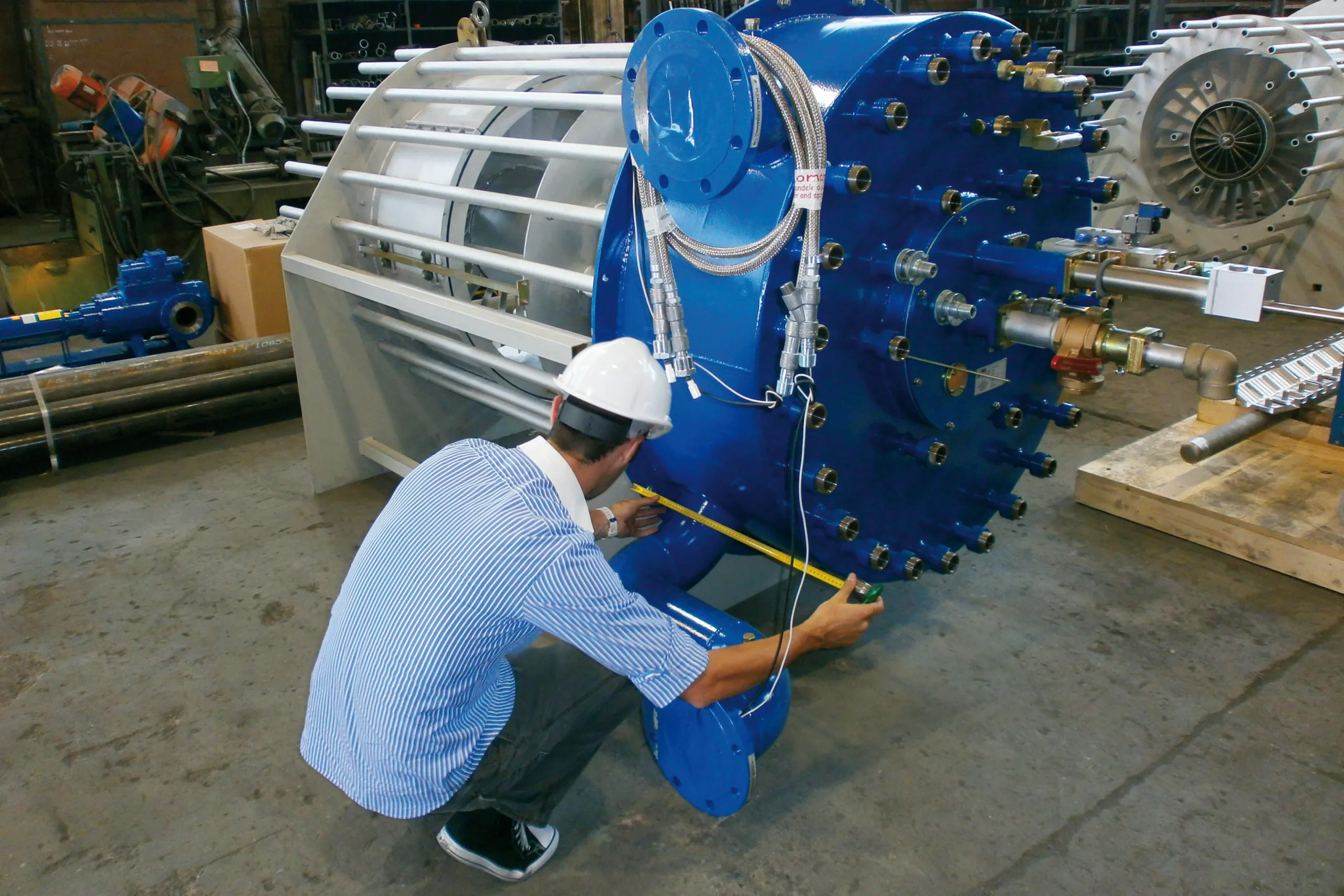 Technician measuring a large industrial burner in the workshop